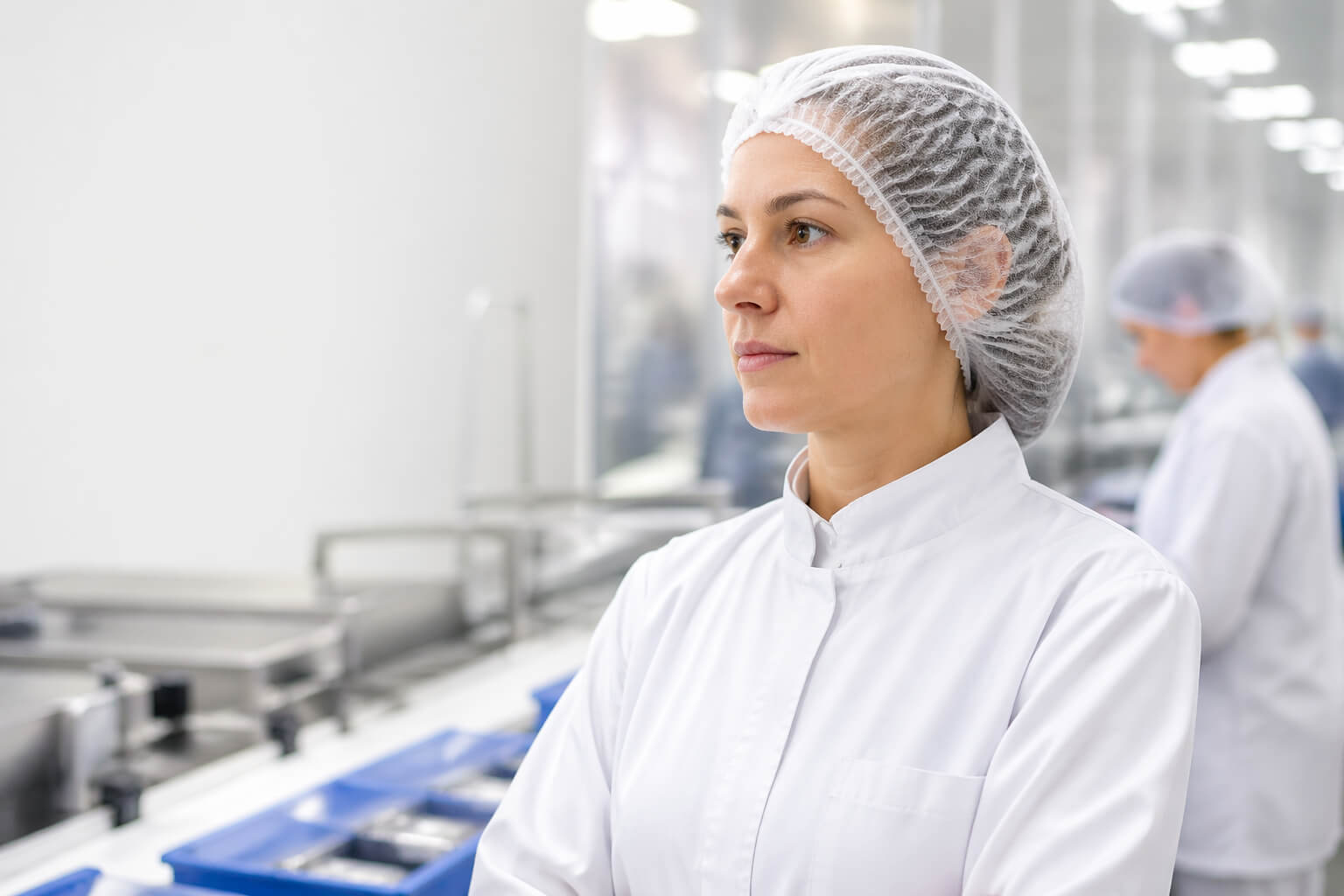 Food processing worker wearing hair net and PPE in clean sanitary production environment
